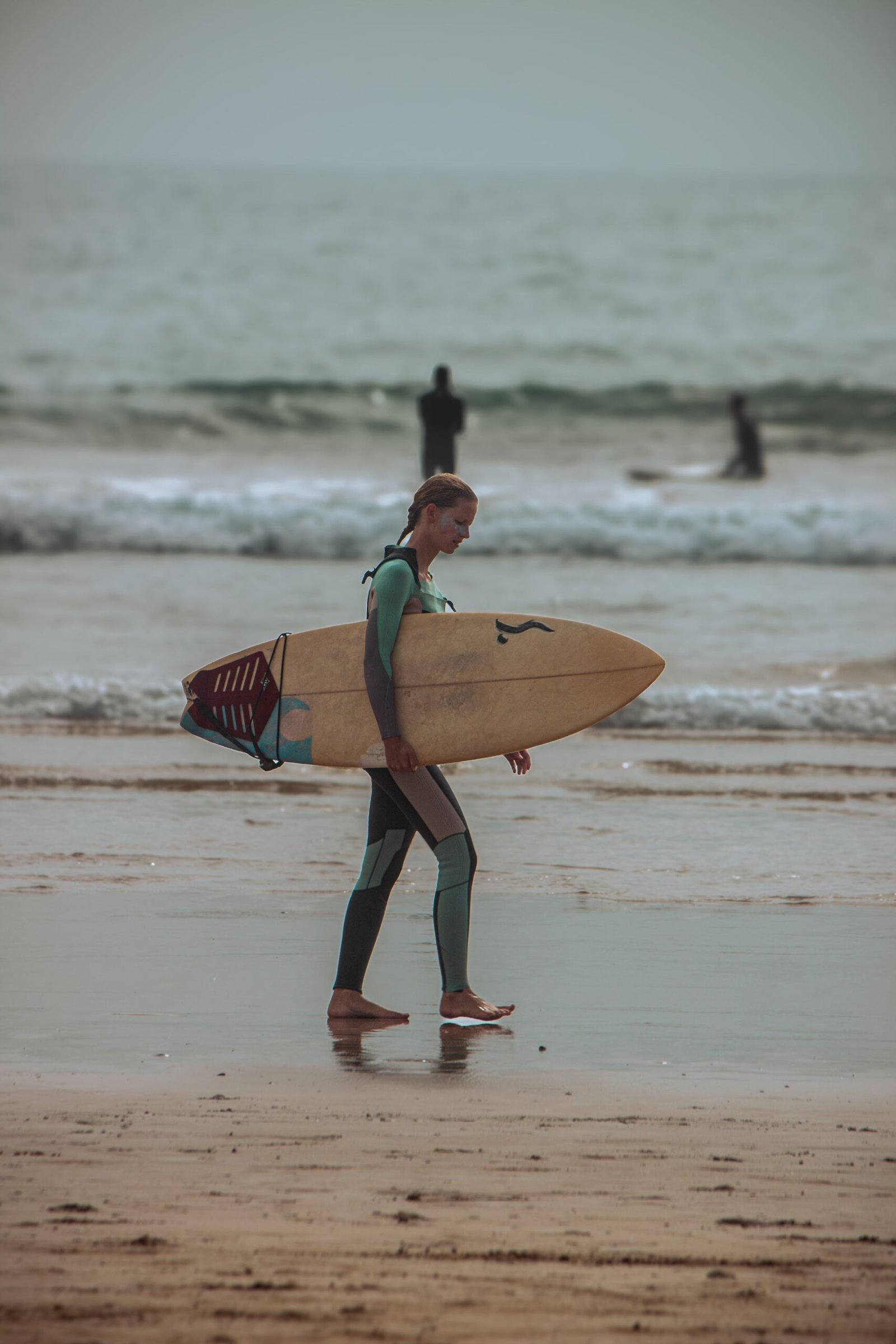 Gallery A surfer carries a surfboard along Taghazout beach, capturing the surf lifestyle in Morocco.