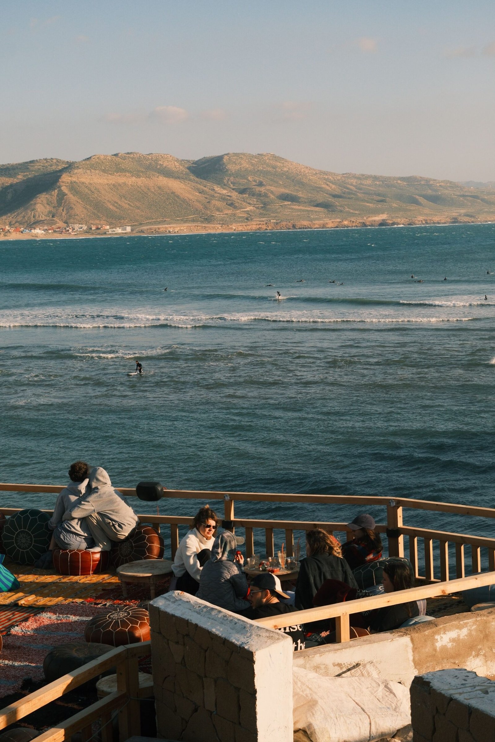 Gallery Relaxed seaside cafe with mountain views and people enjoying the ocean view.